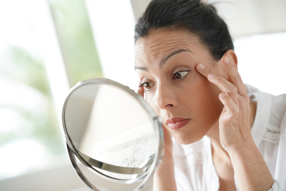 bruenette frau betrachtet gesicht im spiegel - reine haut - kosmetik-studio - stuttgart - carola kiesel - beauty-balance