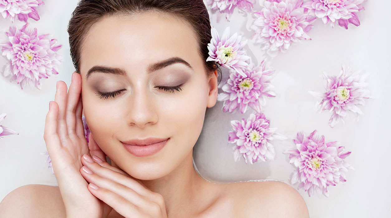 gesicht-junger-frau-umrahmt-von-rosa-blueten frau-spritzt-mit-wasser-gesichtsbehandlung-pflege-kosmetik-studio-stuttgart-carola-kiesel-beauty-balance