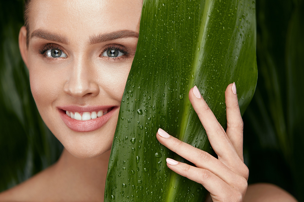 kosmetik-studio-carola-kiesel-stuttgart-beauty-balance - junge Frau mit grossem grünen Blatt neben ihrem Gesicht