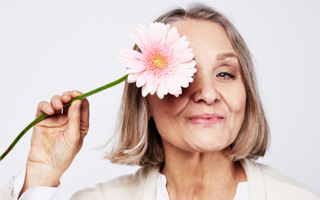 Ältere Frau mit rosa Blume vor dem Auge